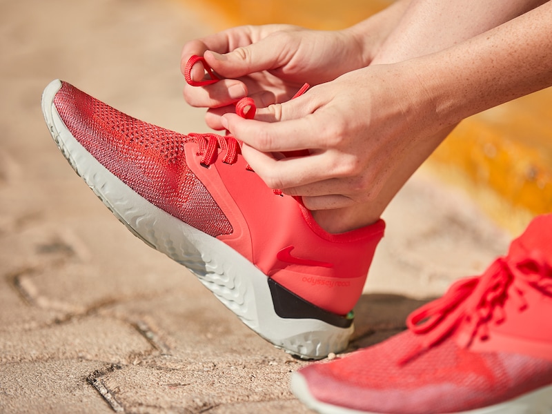 Frau zieht sich rote Laufschuhe an