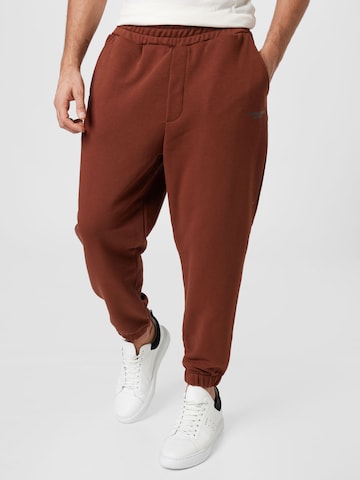 BURTON MENSWEAR LONDON Tapered Trousers in Brown: front