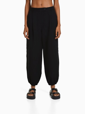 Bershka Tapered Cargo trousers in Black: front