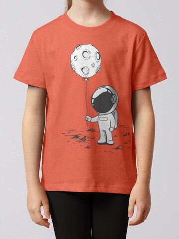 Maglietta 'Kleiner Astronaut mit Luftballon' di watabout.kids in arancione: frontale