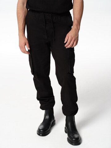 Tapered Pantaloni cargo 'Adriano' di ABOUT YOU x Jaime Lorente in nero: frontale