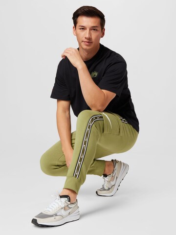 Tapered Pantaloni cu buzunare de la Nike Sportswear pe verde