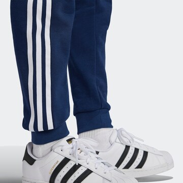 zils ADIDAS ORIGINALS Pakapēniski sašaurināts piegriezums Bikses 'Trefoil'