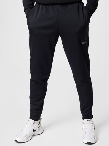 NIKE Tapered Sports trousers in Black: front