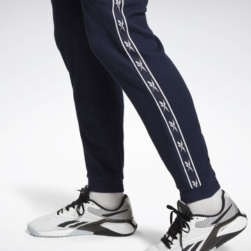 Reebok - Tapered Pantalón deportivo en azul