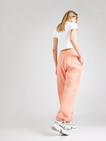 Tapered Pantaloni 'PHNX FLC' de la Nike Sportswear pe portocaliu: spate