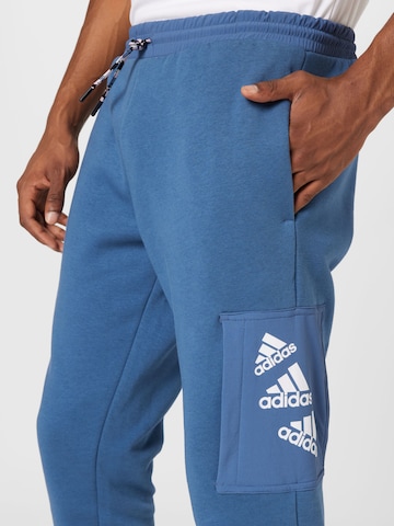 mėlyna ADIDAS SPORTSWEAR Siaurėjantis Sportinės kelnės 'Essentials Brandlove Fleece'
