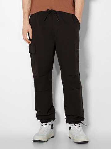 Bershka Loose fit Cargo trousers in Black: front