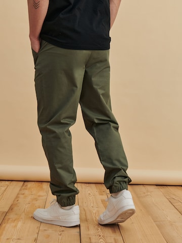 DAN FOX APPAREL Tapered Housut 'Julian' värissä vihreä