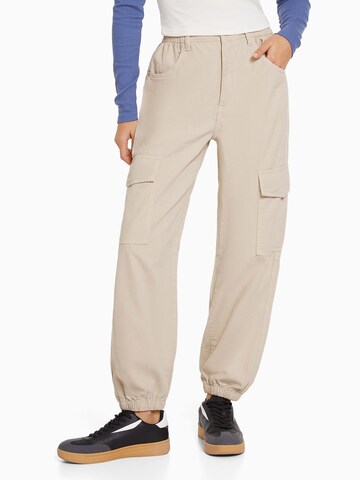 Bershka Tapered Cargo Pants in Beige: front