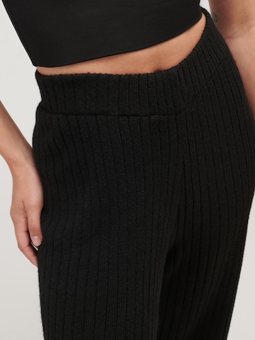 UNFOLLOWED x ABOUT YOU Flared Trousers 'COMFY' in Black