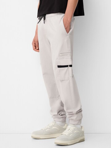 Bershka Tapered Cargo trousers in Grey: front