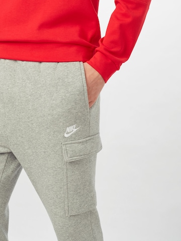 pilka Nike Sportswear Siaurėjantis Laisvo stiliaus kelnės 'Club'