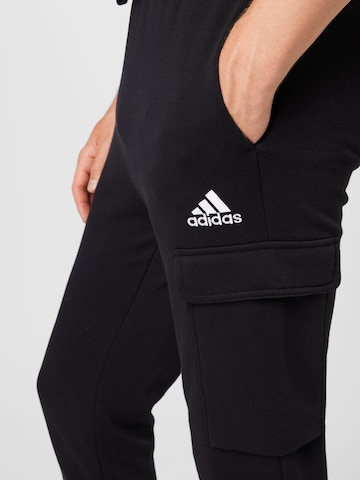 melns ADIDAS SPORTSWEAR Pakapēniski sašaurināts piegriezums Sporta bikses 'Essentials Fleece'