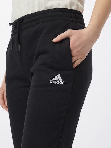 melns ADIDAS SPORTSWEAR Pakapēniski sašaurināts piegriezums Sporta bikses 'Essentials Fleece Logo'