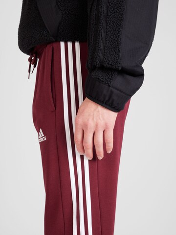 ADIDAS SPORTSWEAR Tapered Urheiluhousut 'Essentials' värissä punainen