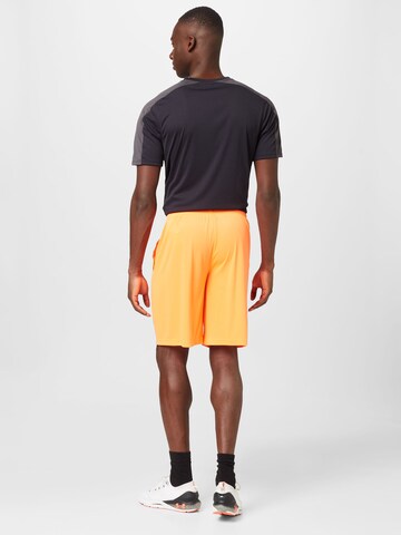 UNDER ARMOUR Lużny krój Spodnie sportowe w kolorze pomarańczowy