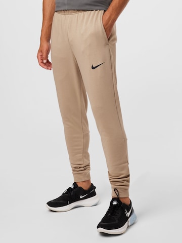 NIKE Tapered Sports trousers in Beige: front