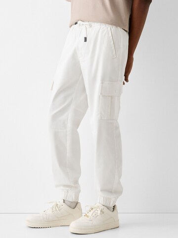 Bershka Tapered Cargo Pants in White: front