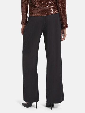 Nicowa Slimfit Anzughose 'ROSCIWO', weites Bein, Bundfalten, Model trägt Größe 34 in Braun