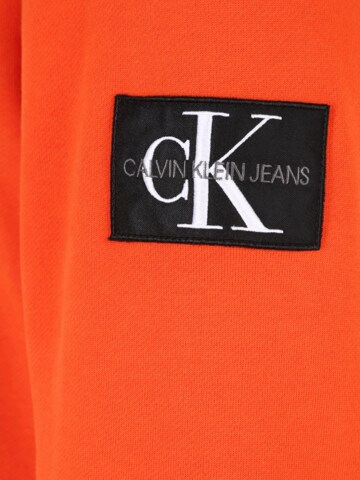 Calvin Klein Jeans جينز مضبوط كنزة رياضية بلون برتقالي