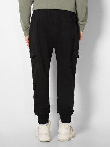 Bershka Tapered Chinohousut värissä musta