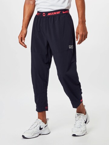 NIKE Tapered Sports trousers in Black: front