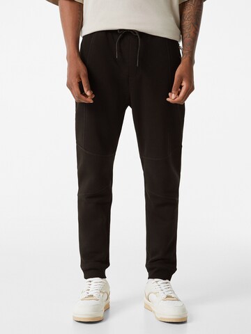 Bershka Tapered Pants in Black: front