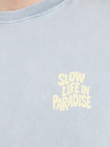 Maglietta 'SLOW LIFE IN PARADISE' di Kaotiko in grigio