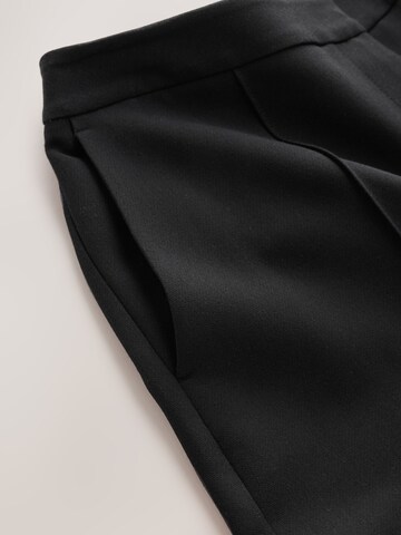 Flared Pantaloni con piega frontale di Next in nero