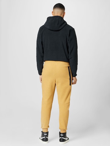 Tapered Pantaloni di Nike Sportswear in giallo