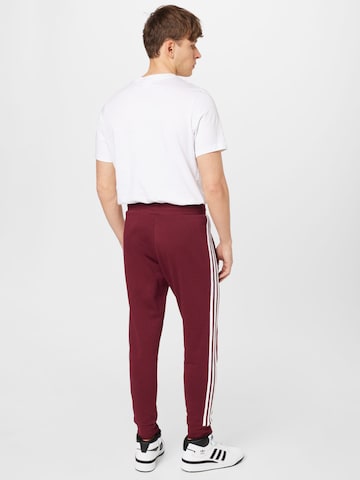 ADIDAS ORIGINALS Slimfit Housut 'Adicolor Classics' värissä punainen