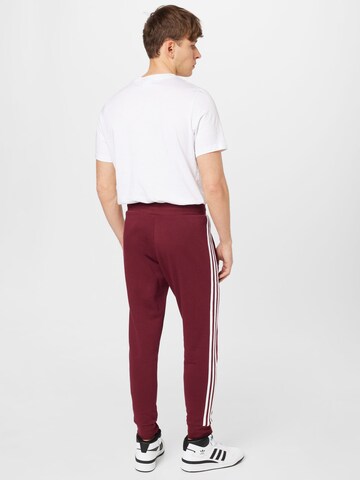 ADIDAS ORIGINALS Slimfit Housut 'Adicolor Classics' värissä punainen