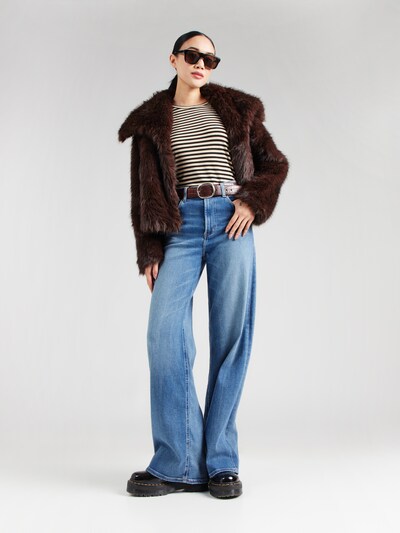 Woman in brown fur coat with striped shirt and jeans