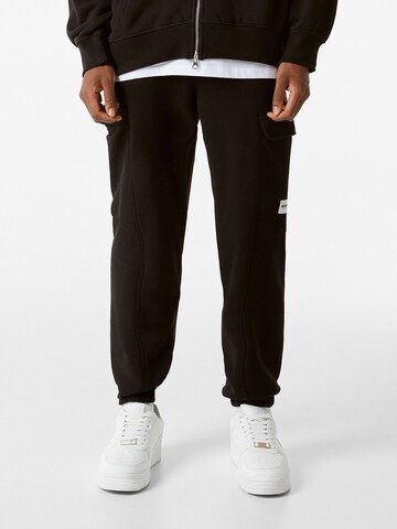 Bershka Tapered Cargo trousers in Black: front