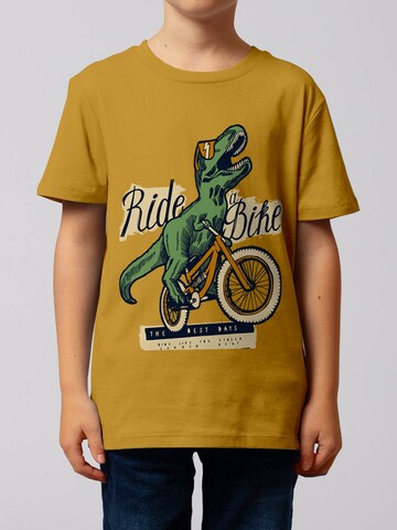 watabout.kids Shirt 'T-Rex Fahrrad' in Geel: voorkant