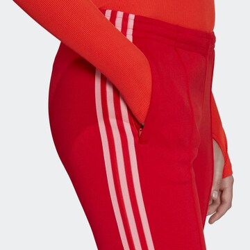 ADIDAS ORIGINALS Levenevä Housut 'Adicolor 70S ' värissä punainen