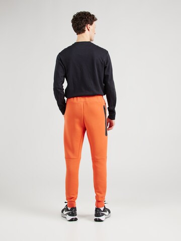 Nike Sportswear Tapered Παντελόνι 'TCH FLC' σε πορτοκαλί