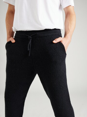Tapered Pantaloni 'Taylan' di ABOUT YOU x Jaime Lorente in nero
