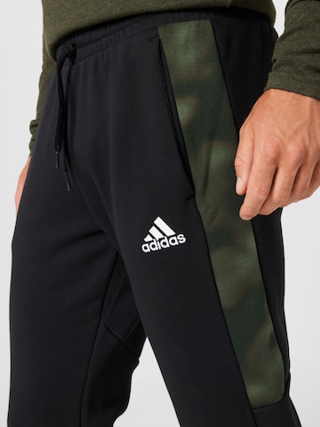 ADIDAS SPORTSWEAR Tapered Sportbroek 'Essentials Camo' in Zwart