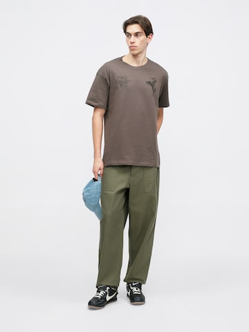 Nike Sportswear Póló 'M90 OC WINGS VICTORY' - szürke