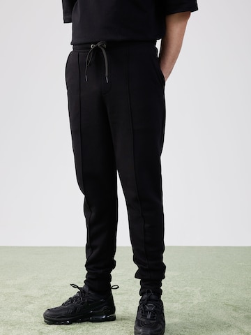 ABOUT YOU x Rewinside Tapered Pants in Black: front
