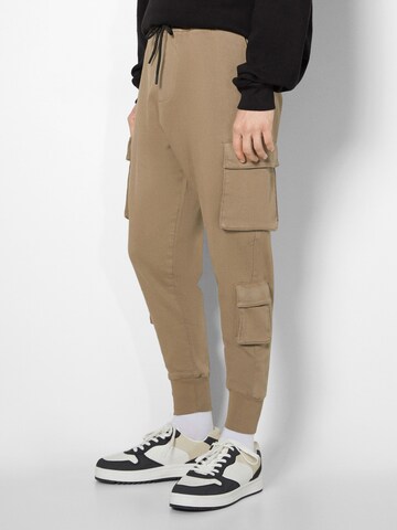 Bershka Tapered Cargo trousers in Beige: front