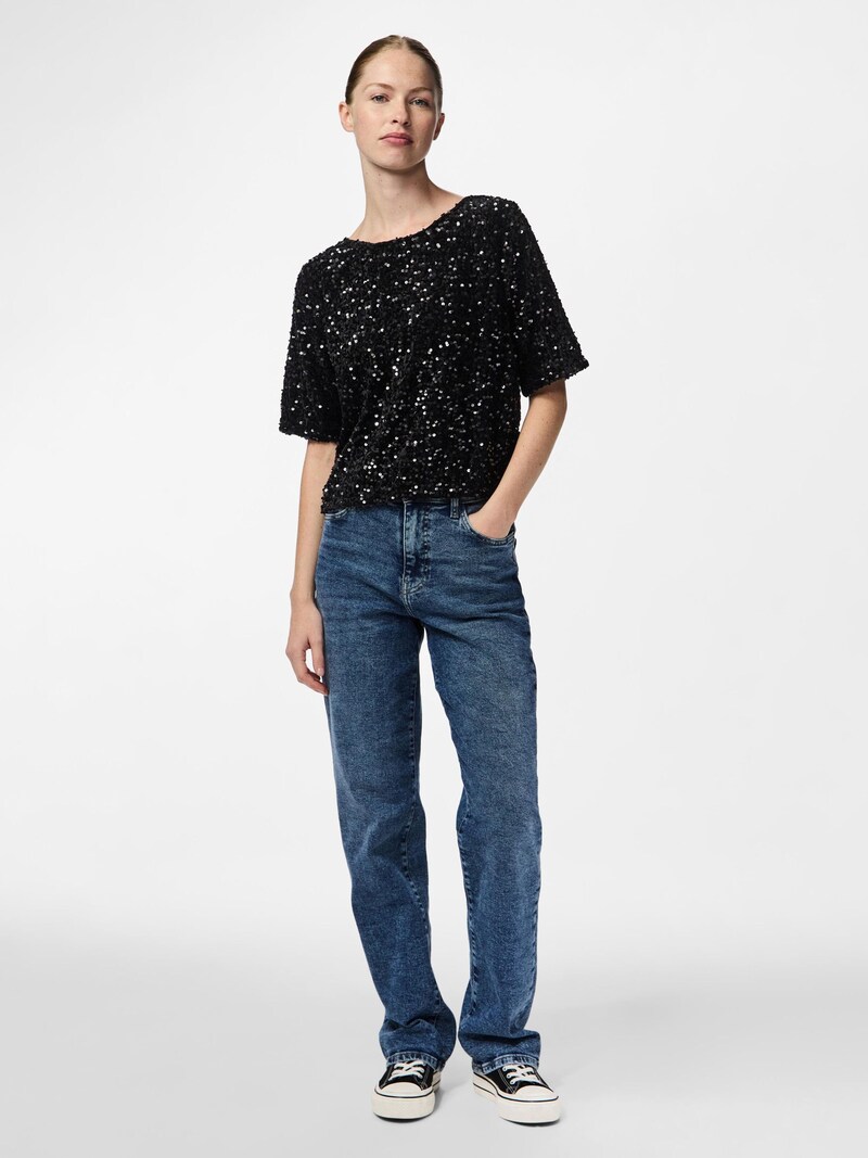 Woman in black sequin top with dark-wash jeans