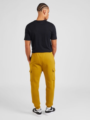 geltona Nike Sportswear Siaurėjantis Laisvo stiliaus kelnės 'CLUB'