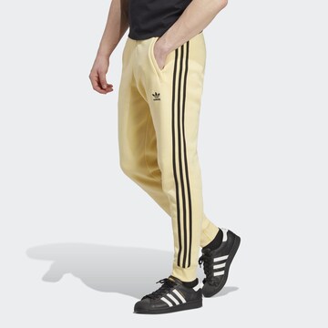 ADIDAS ORIGINALS Slimfit Housut 'Adicolor Classics' värissä keltainen