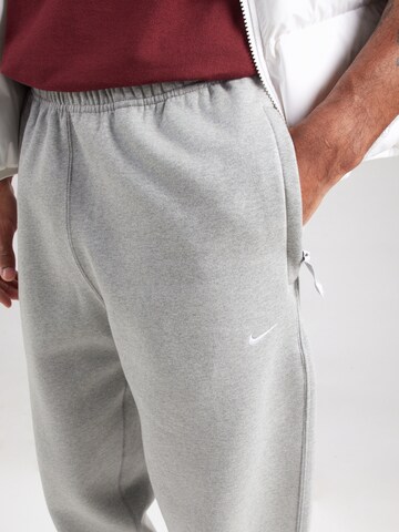 pelēks Nike Sportswear Pakapēniski sašaurināts piegriezums Bikses 'Swoosh'