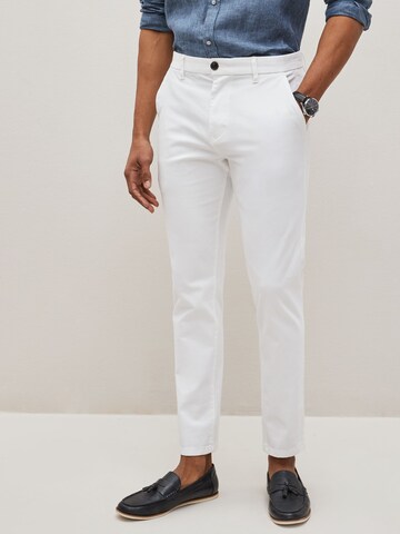 Next Slimfit Chinohousut värissä valkoinen