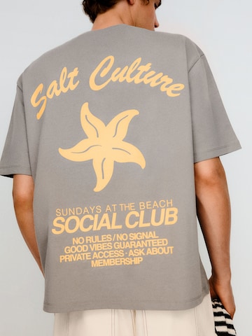 Bershka T-shirt 'PARADISE CLUB' i grå