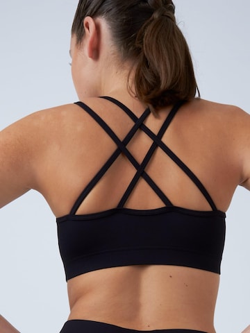 Medium Support Soutien-gorge de sport 'Crossed Straps' SPORTKIND en noir